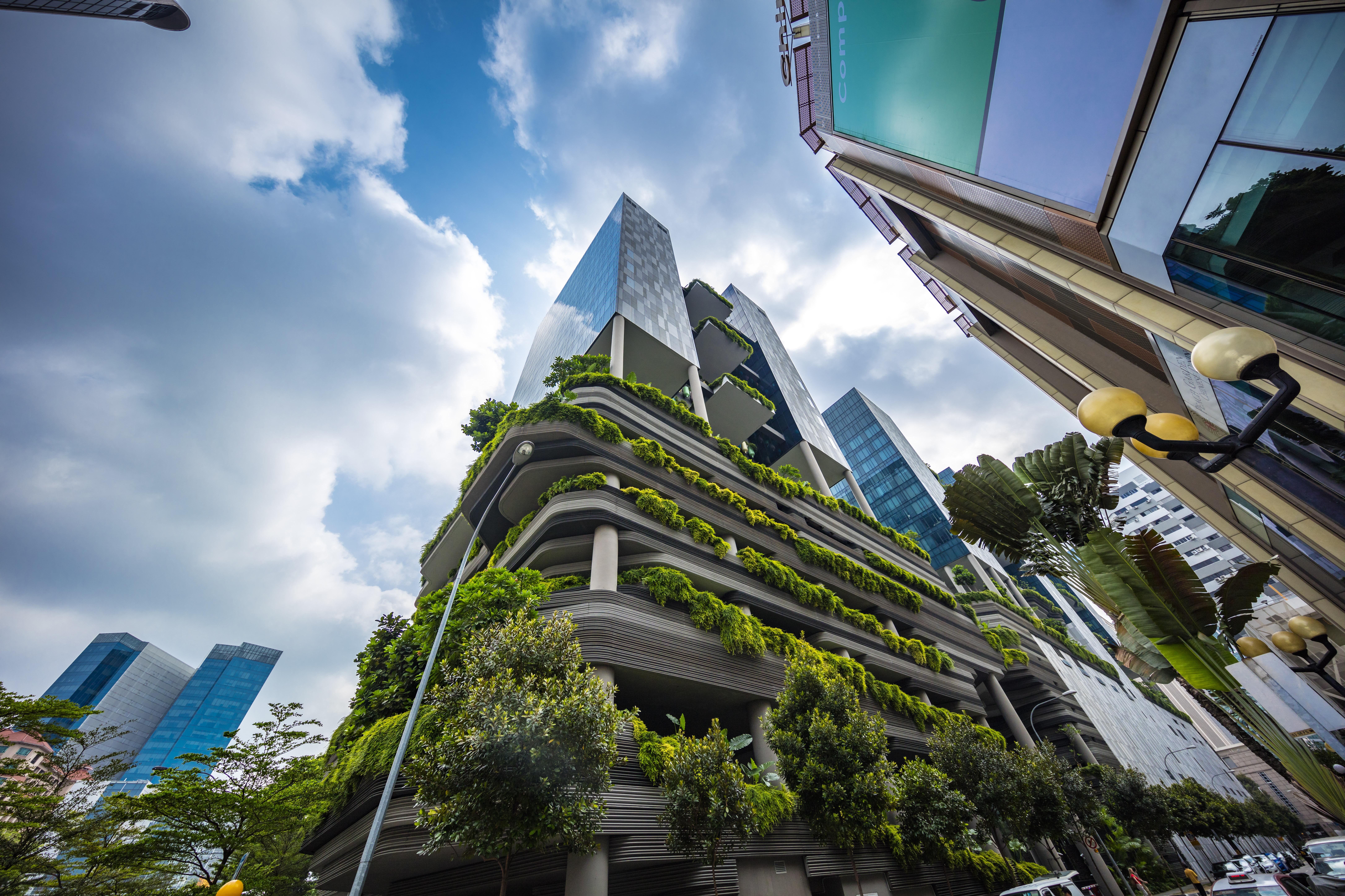 فندق Parkroyal Collection Pickering, سنغافورة المظهر الخارجي الصورة The photo shows a modern urban setting featuring contemporary buildings. In the foreground, there is a distinctive structure with a green façade, showcasing various plants and greenery integrated into the architecture. The design appears to emphasize