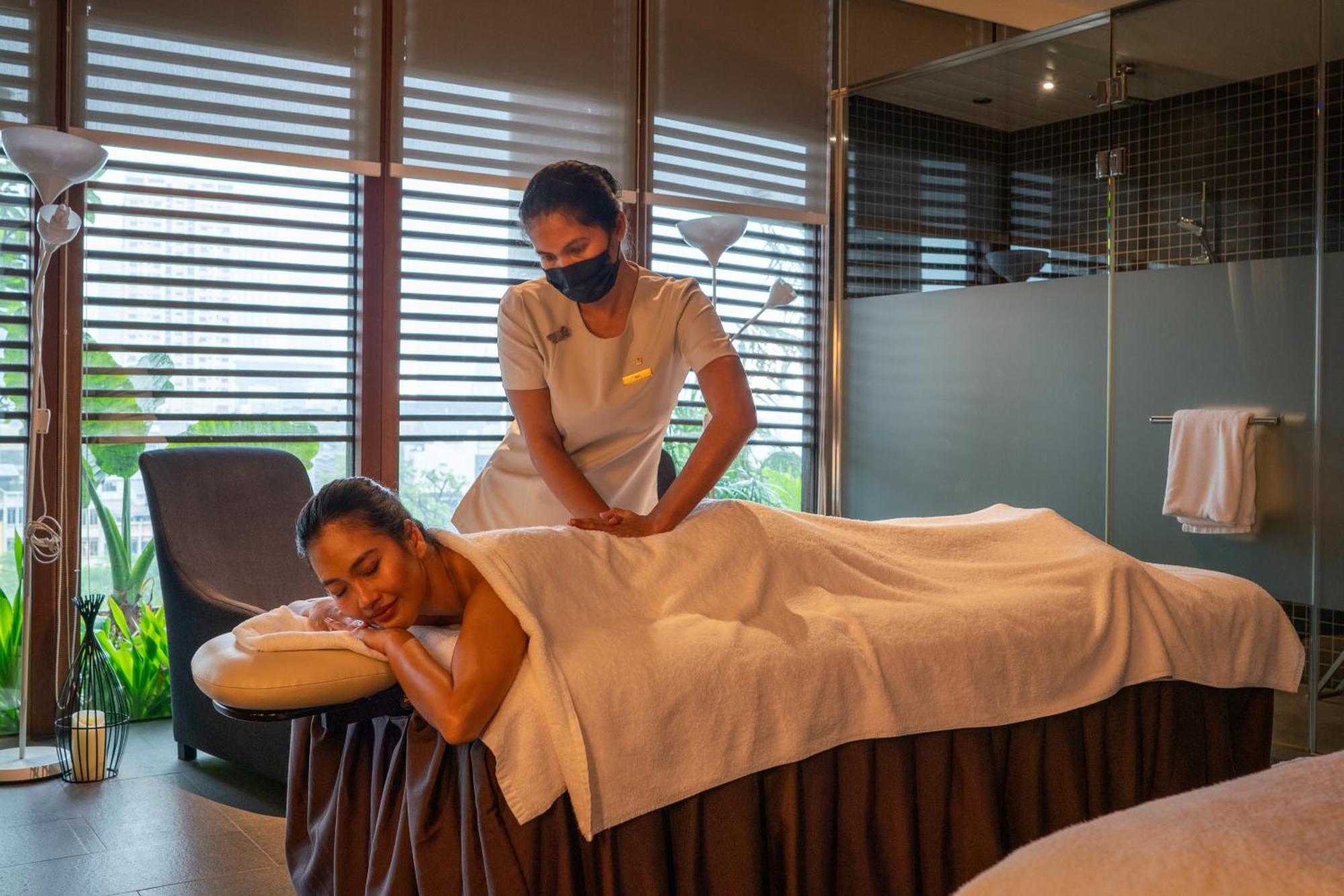 فندق Parkroyal Collection Pickering, سنغافورة المظهر الخارجي الصورة The photo shows a serene spa setting where a therapist is giving a massage to a client. The client is lying face down on a massage table, covered with a towel, and appears to be relaxed. The therapist is positioned at the client's back, providing the